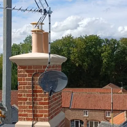 A dish and aerial on a chimney stack, rooftops running away behind.
