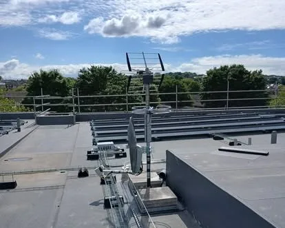 A row of aerials mounted on a rail across a flat commercial roof.