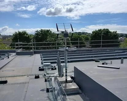 A row of aerials mounted on a rail across a flat commercial roof.