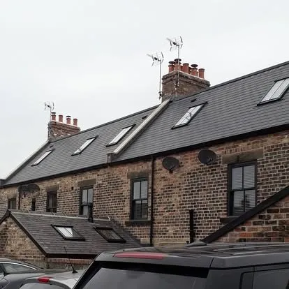 Aerials and chimney stacks along a row of stone terraced houses.